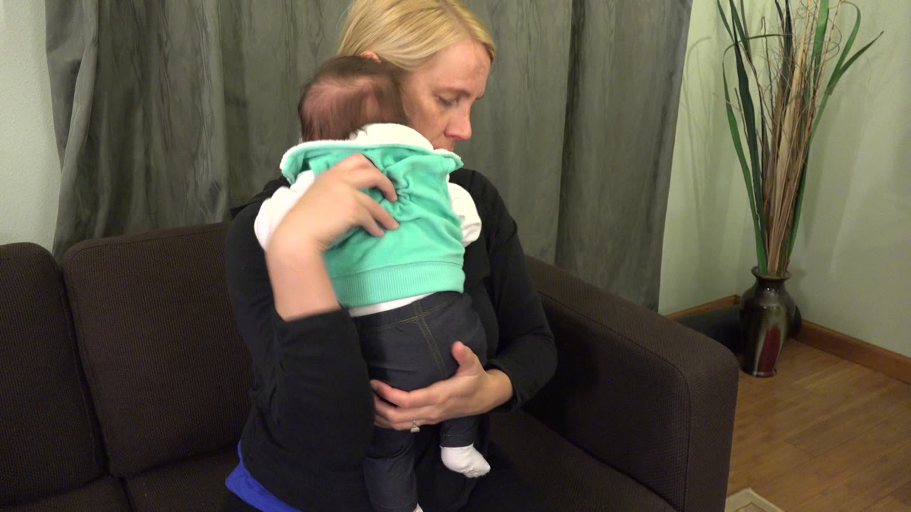Mother looking down while supporting baby.
