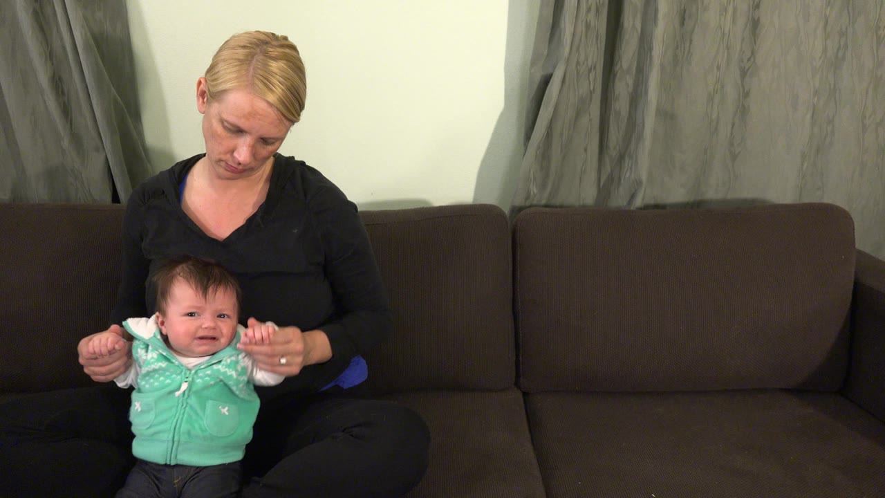 Baby faces forward while the mother supports both arms.