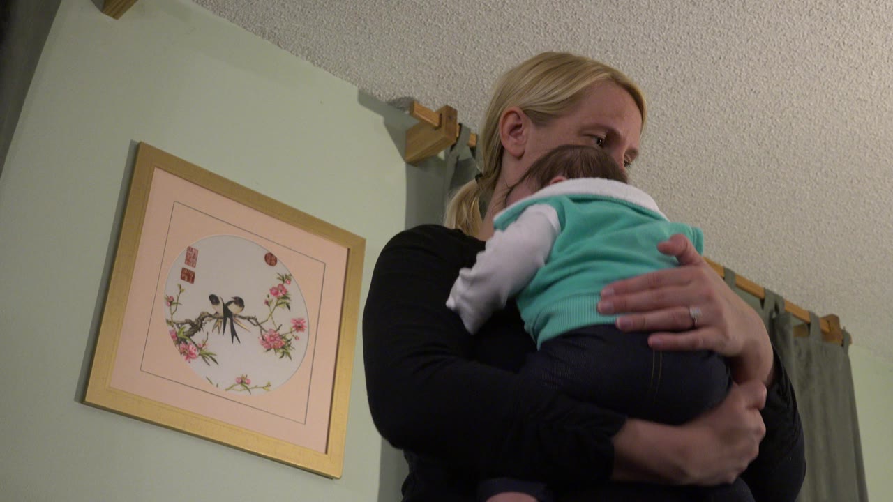 Older woman holding a baby against her shoulder indoors