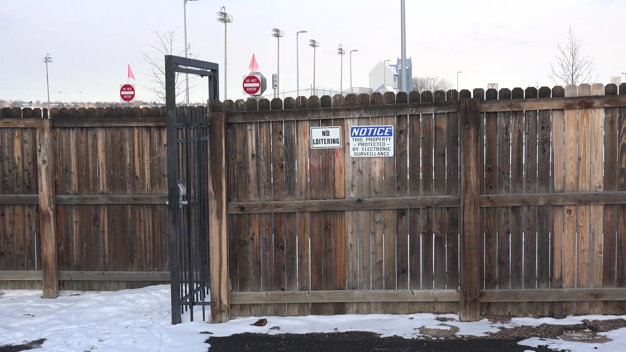 The Westminster fence remains centered, showing vertical wood boards, a black gate at left, snow below, and no visible people.
