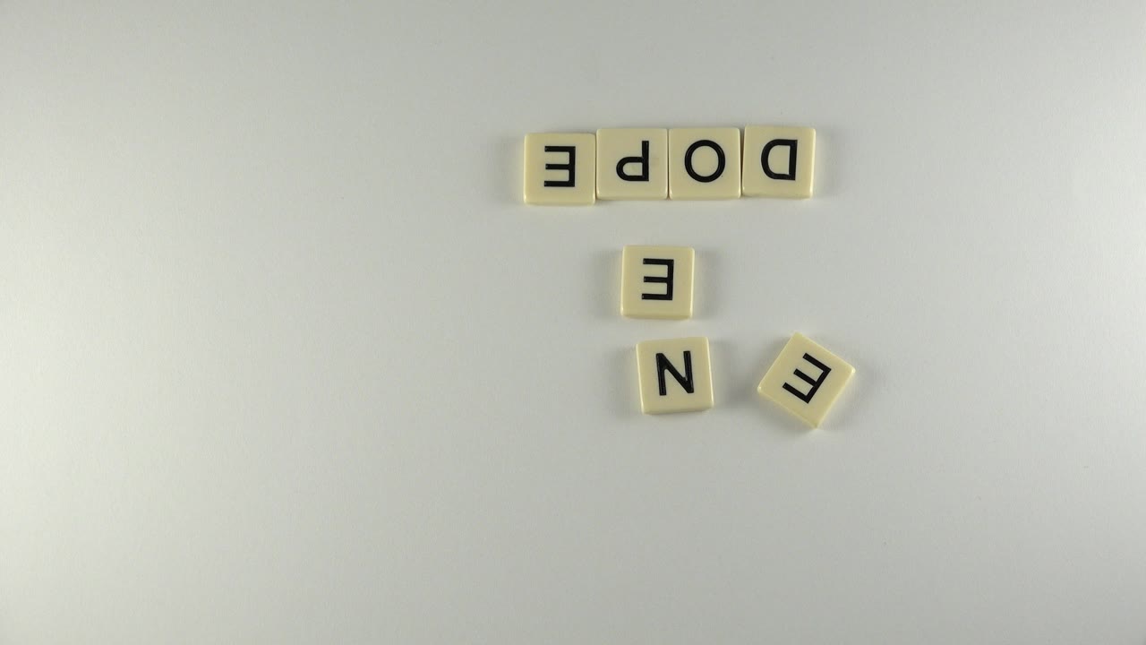 Second overhead frame in Westminster, Colorado shows the same cream tiles spelling DOPE and NEED, with a separate E tile angled to the right and no visible people.