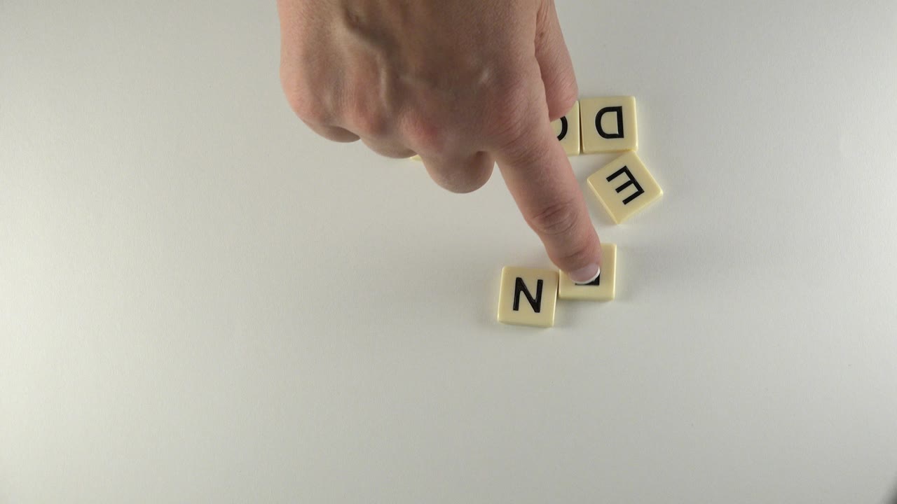 In Westminster, Colorado, the hand holds one tile in place while the N tile remains lower left and the E and D tiles sit near the top edge.