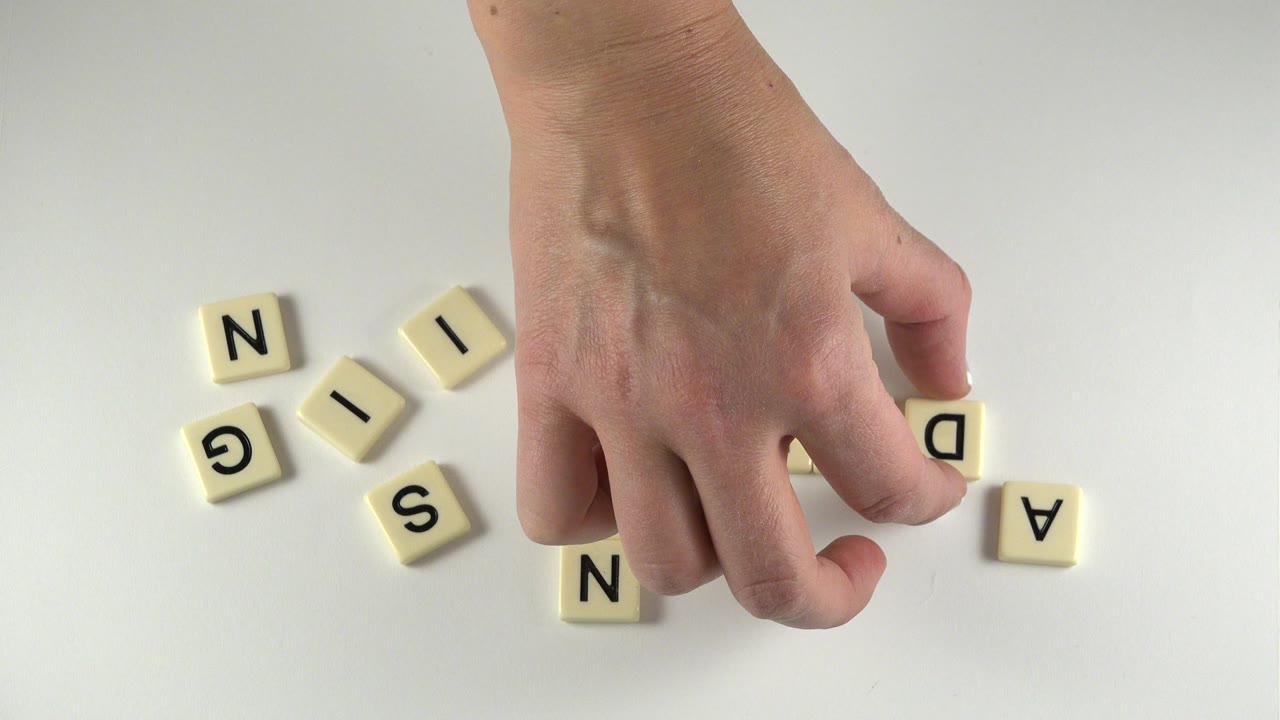 At 0:00 in Westminster, Colorado, a hand hovers over scattered cream letter tiles on a pale tabletop, with no visible faces.