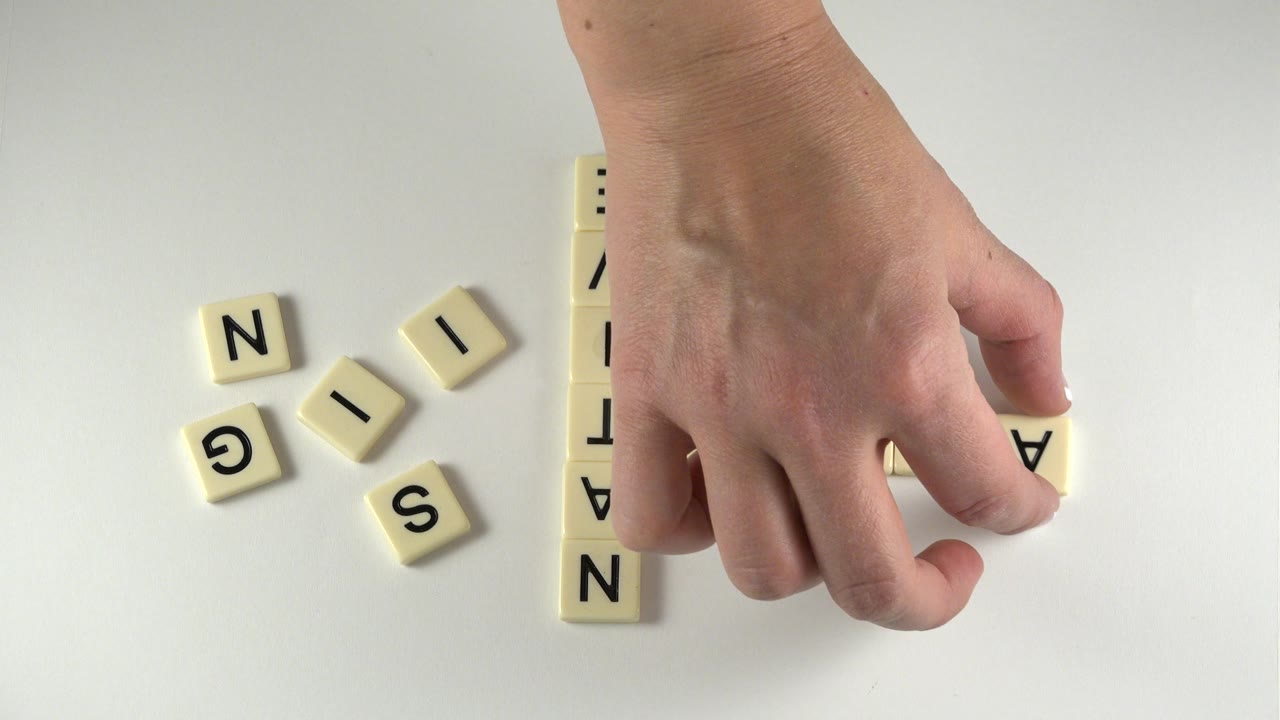 Hand placing a tile near the start of a vertical word.