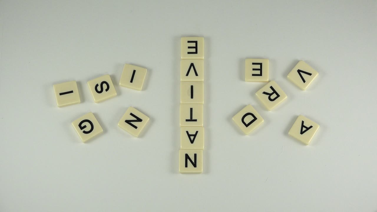 An overhead frame shows the same cream letter tiles around the vertical NAT-IVE arrangement on a pale Westminster, Colorado surface, with no visible people.