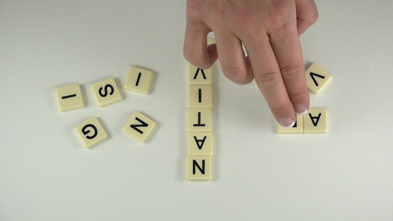 At 0:01 in Westminster, Colorado, the hand presses a cream letter tile near a short horizontal arrangement while NATIVE remains vertical on the tabletop.