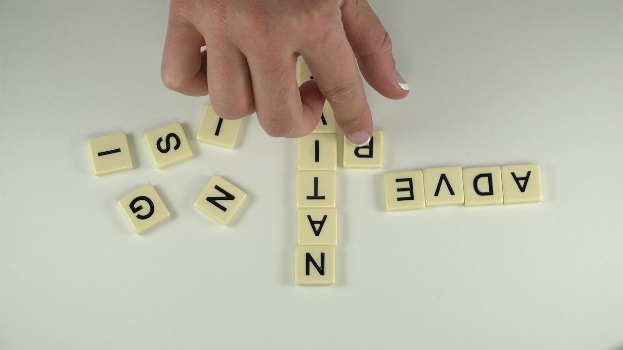 Child's hand above letter tiles on a white table.