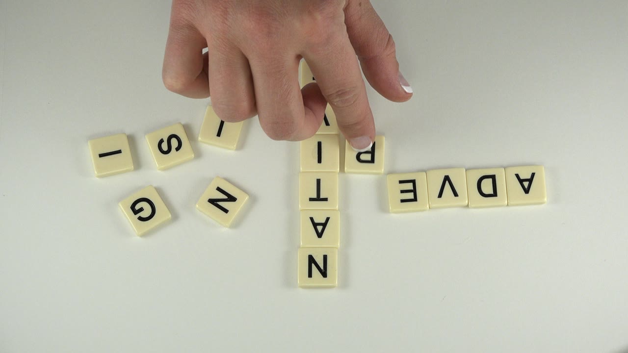 One second in, the child's finger presses near the crossing letter tiles, with NATIVE vertical and ADVERT horizontal on the white table in Westminster, Colorado.