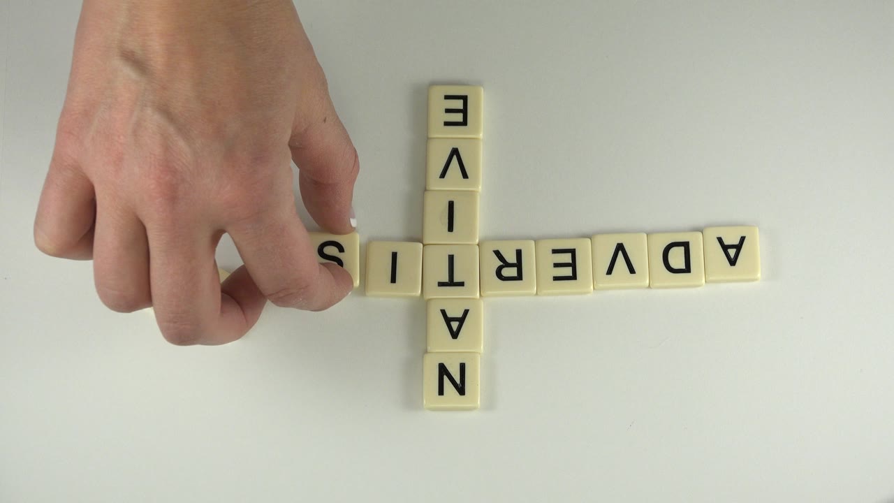 Hand setting a tile near a crossed native and adverti layout.