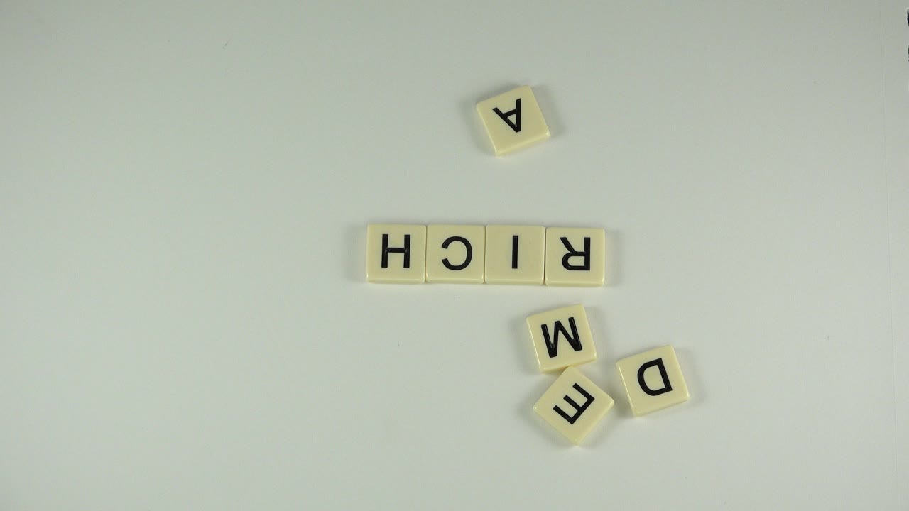 Letter tiles spelling RICH with loose tiles on a pale tabletop.