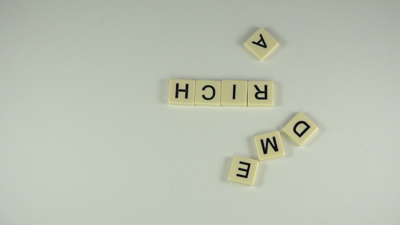Letter tiles spelling RICH with loose A, D, M, and E tiles on a pale tabletop.