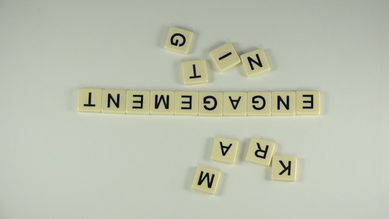 Letter tiles spelling ENGAGEMENT with loose tiles on a pale tabletop.