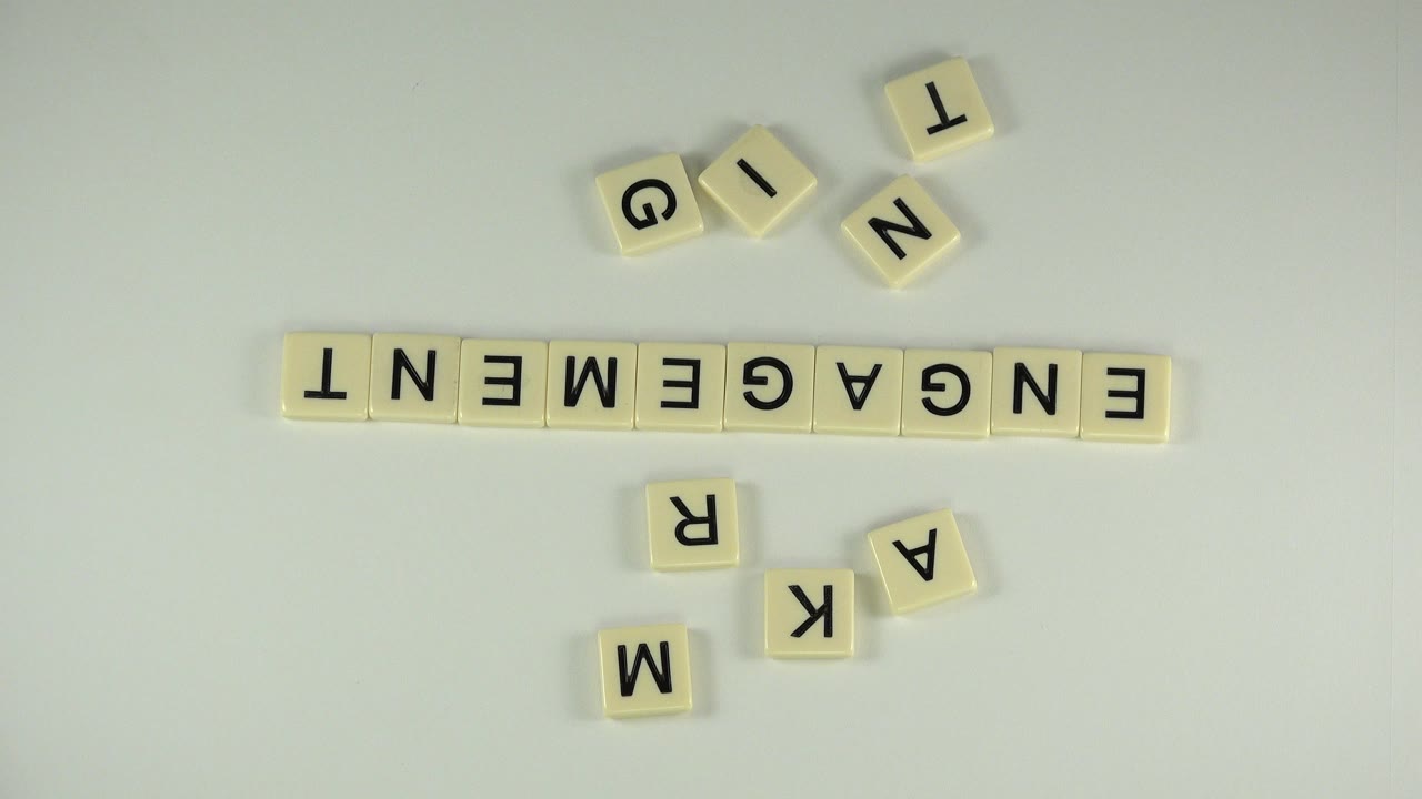 Overhead view in Westminster, Colorado of cream letter tiles spelling ENGAGEMENT with loose tiles around them and no visible people.