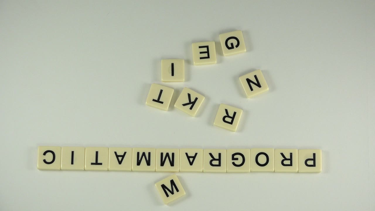 Cream letter tiles spell PROGRAMMATIC upside down on a pale tabletop.