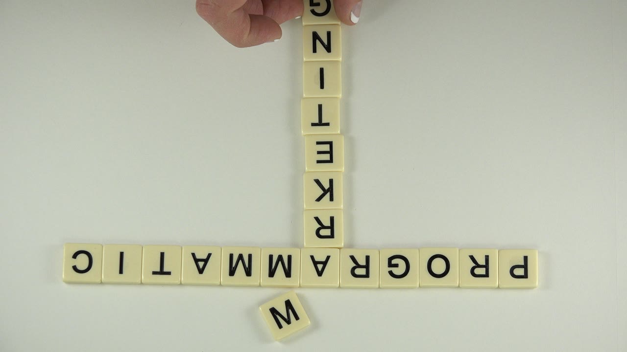At 0:01 in Westminster, Colorado, the same letter-block arrangement fills the frame as an adult hand hovers above the vertical word near the top border.