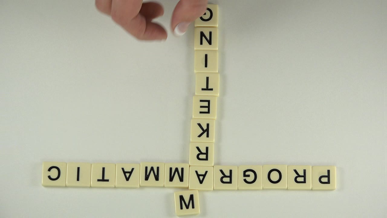 Hand above cream letter tiles on a pale tabletop.
