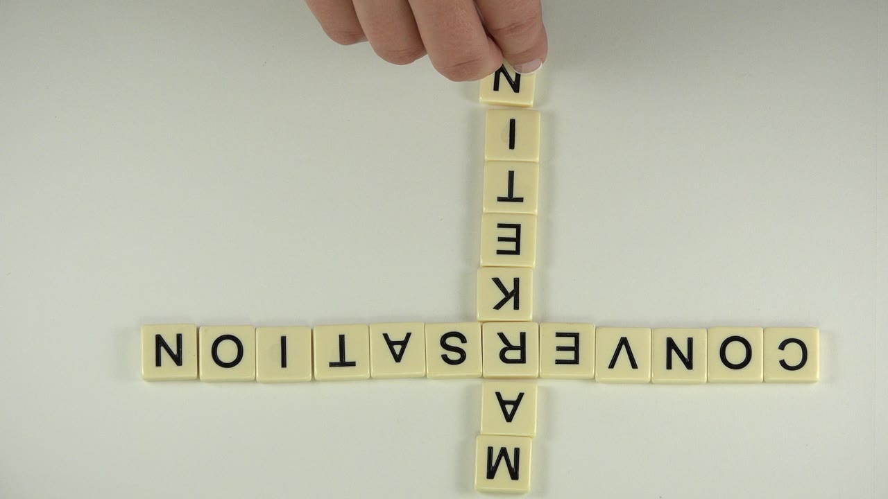 At 0:00 in the Westminster, Colorado clip, cream letter tiles spell CONVERSATION across and MARKETING down in an inverted cross while fingertips hold the top tile area.