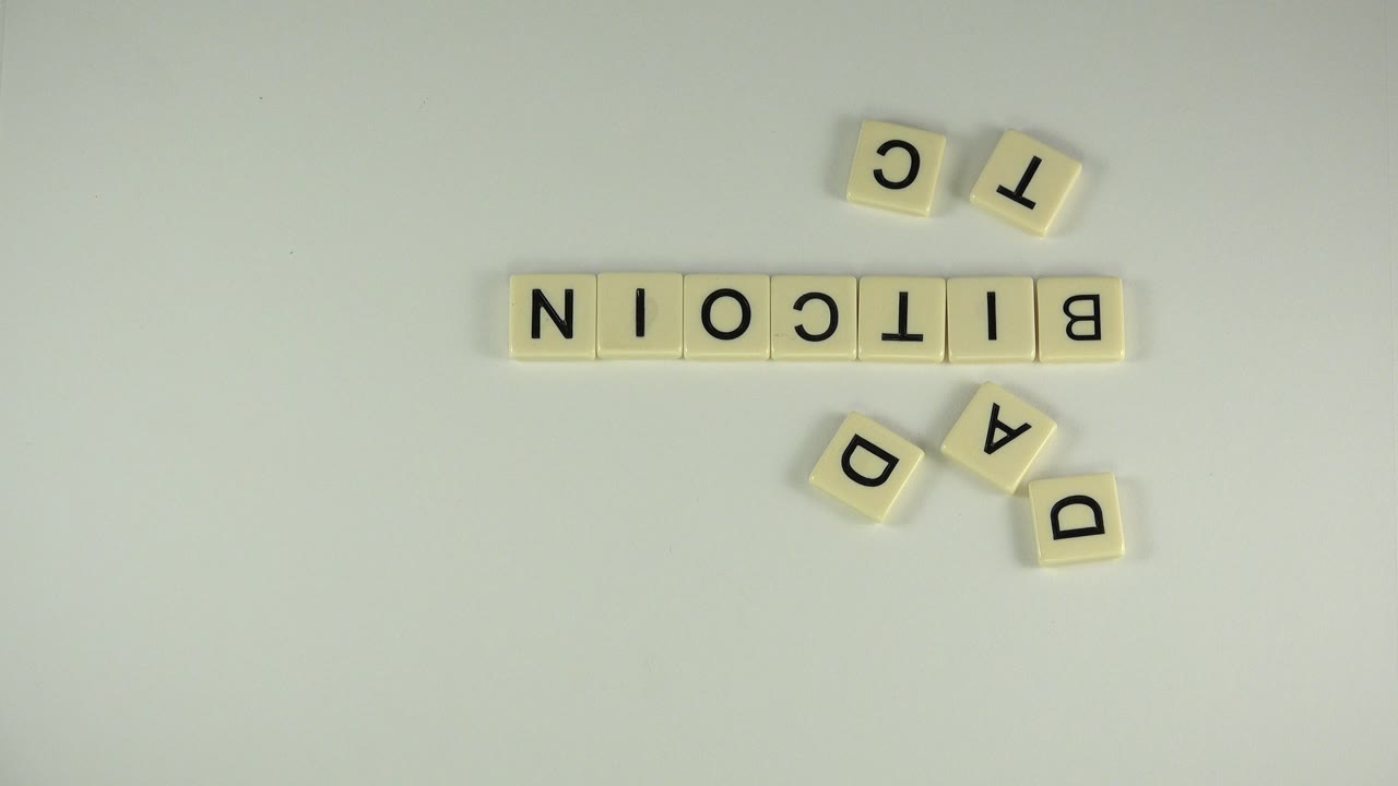 Plastic letter tiles spelling BITCOIN on a pale tabletop.