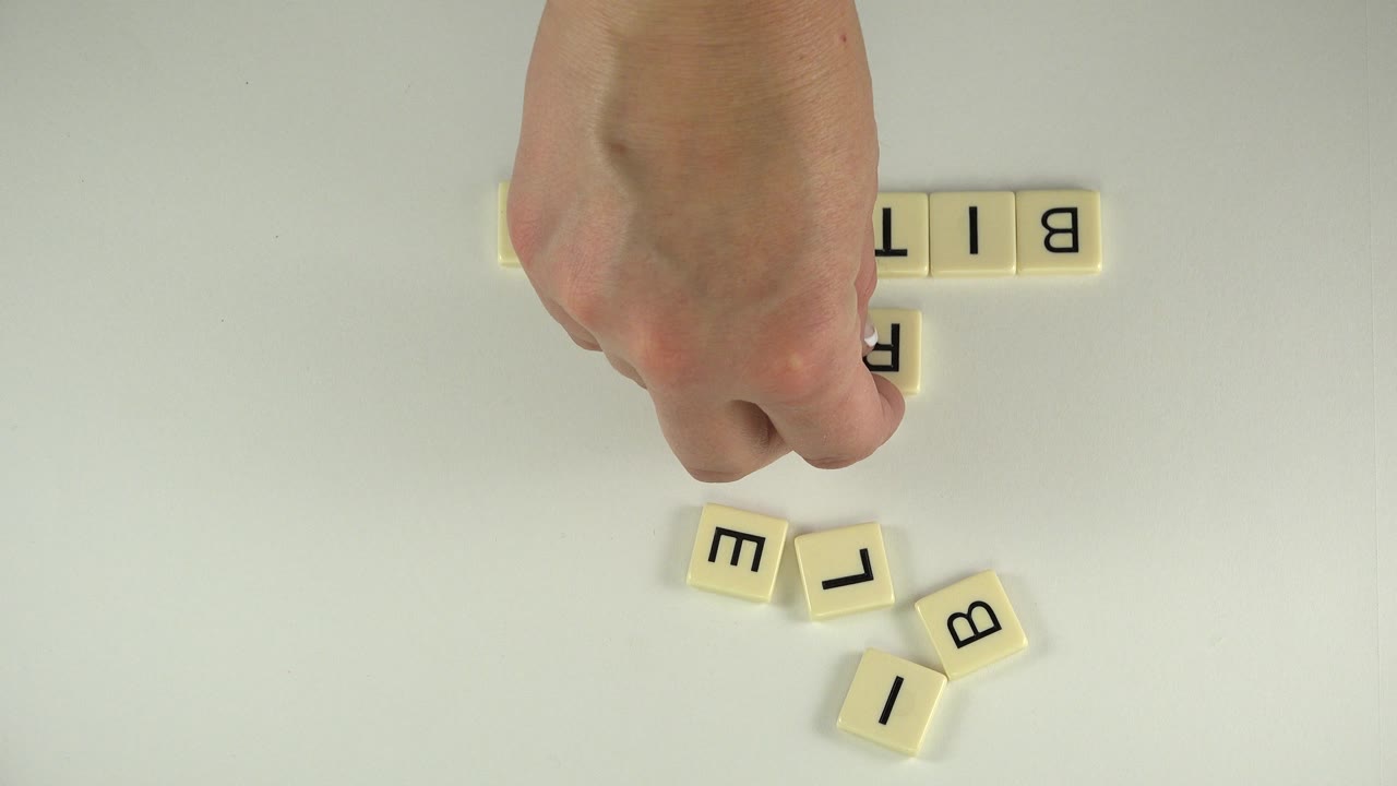 Hand places a letter tile below a row of word-game tiles.