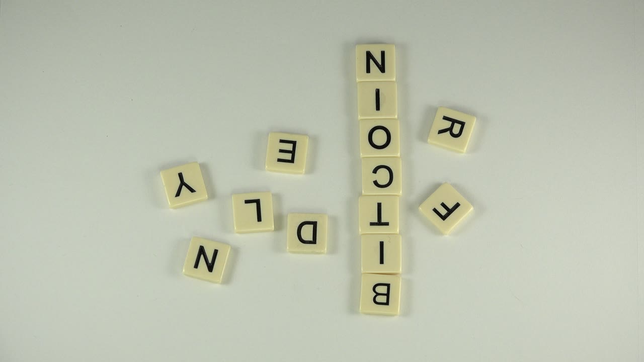 BITCOIN spelled in tiles beside scattered letters on a tabletop.