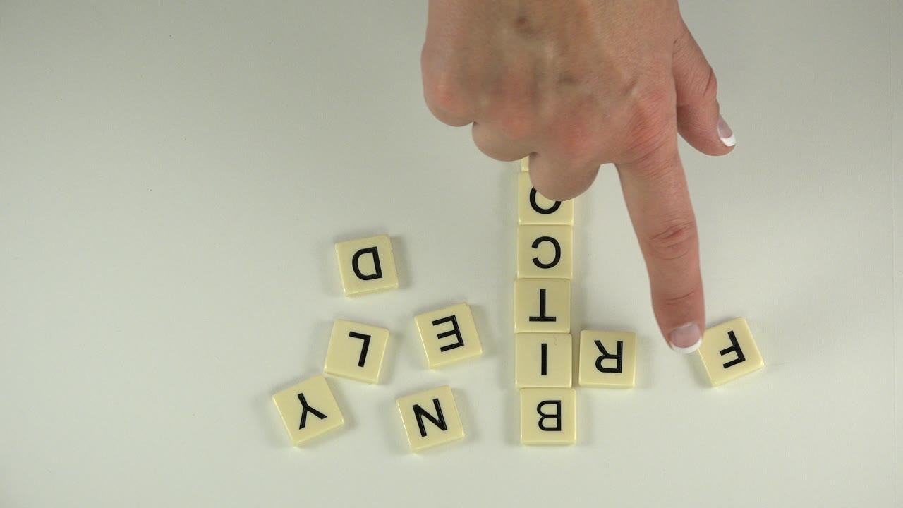 In Westminster, Colorado, the finger points lower beside the vertical Bitcoin tiles while loose letters including D, L, E, N, Y, and F sit around the arrangement.