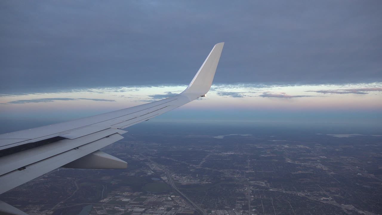 Airplane wing over dark terrain and distant water