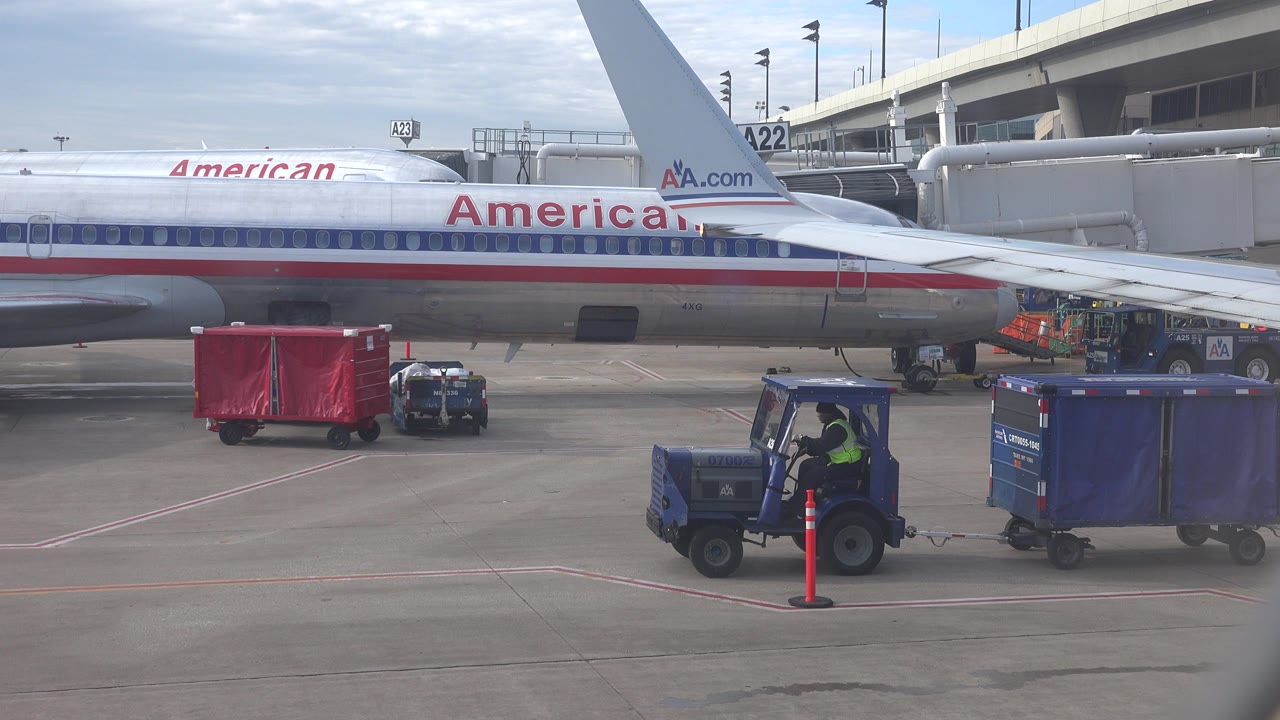 American Airlines plane at gate with baggage tug and carts on the tarmac