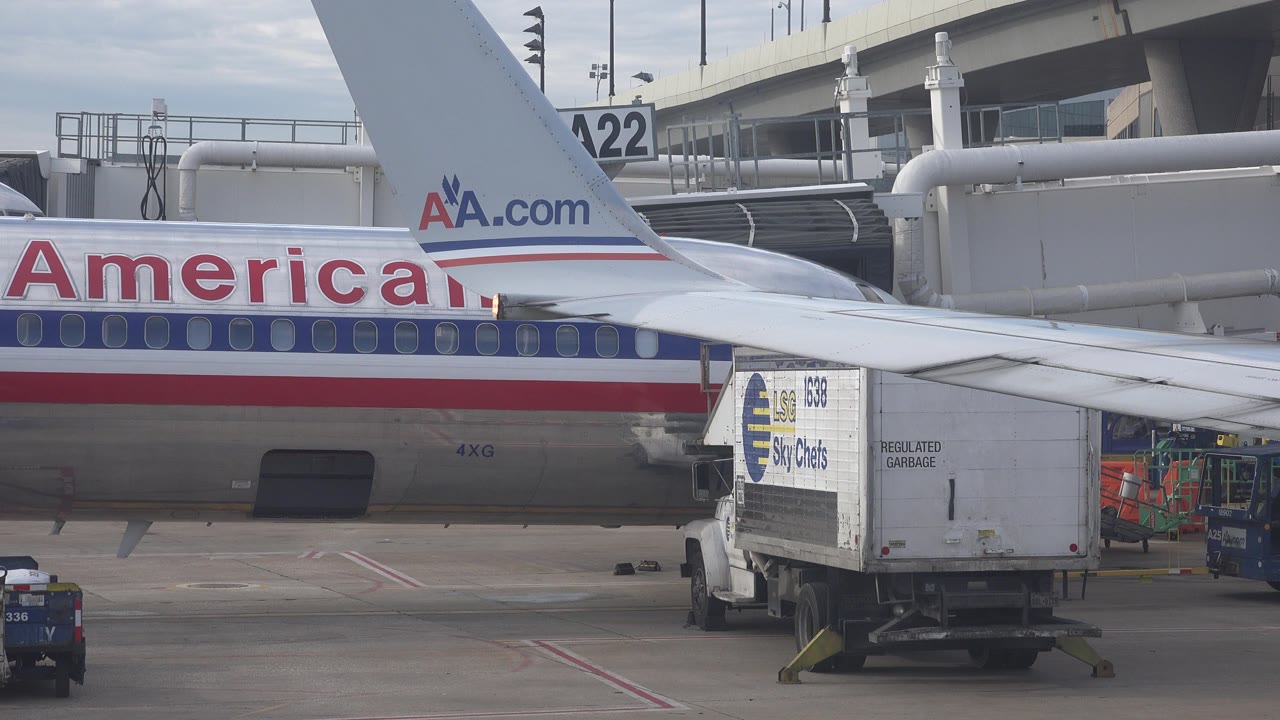 American Airlines aircraft at an airport gate in Playa Del Carmen, Mexico, with a catering truck parked below the wing and no visible people.