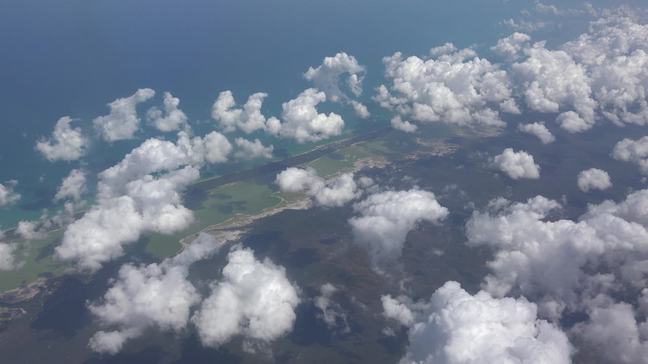 Cloud clusters over blue water and a narrow coastal strip.