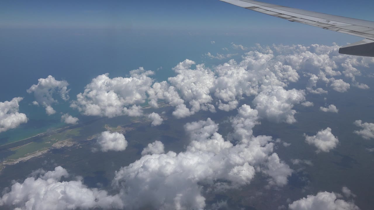 Aircraft wing over ocean clouds and land edge
