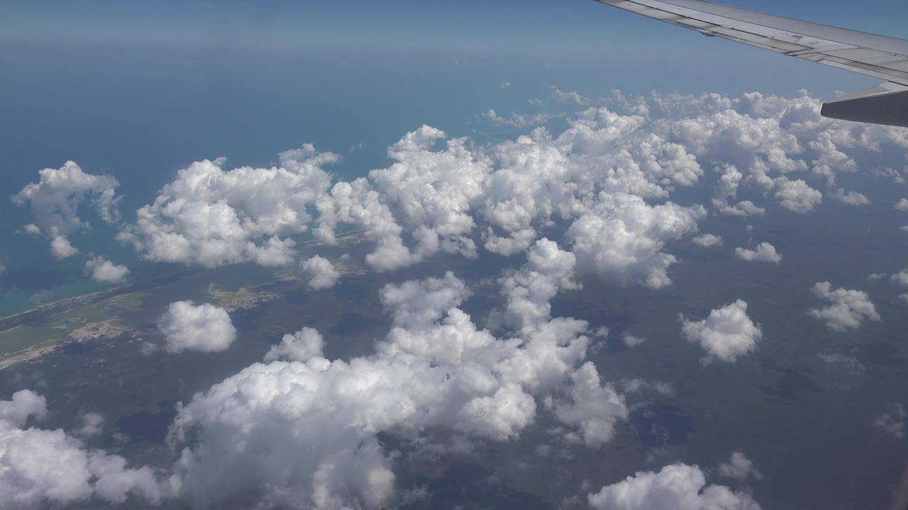 Airplane wing and bright clouds over water