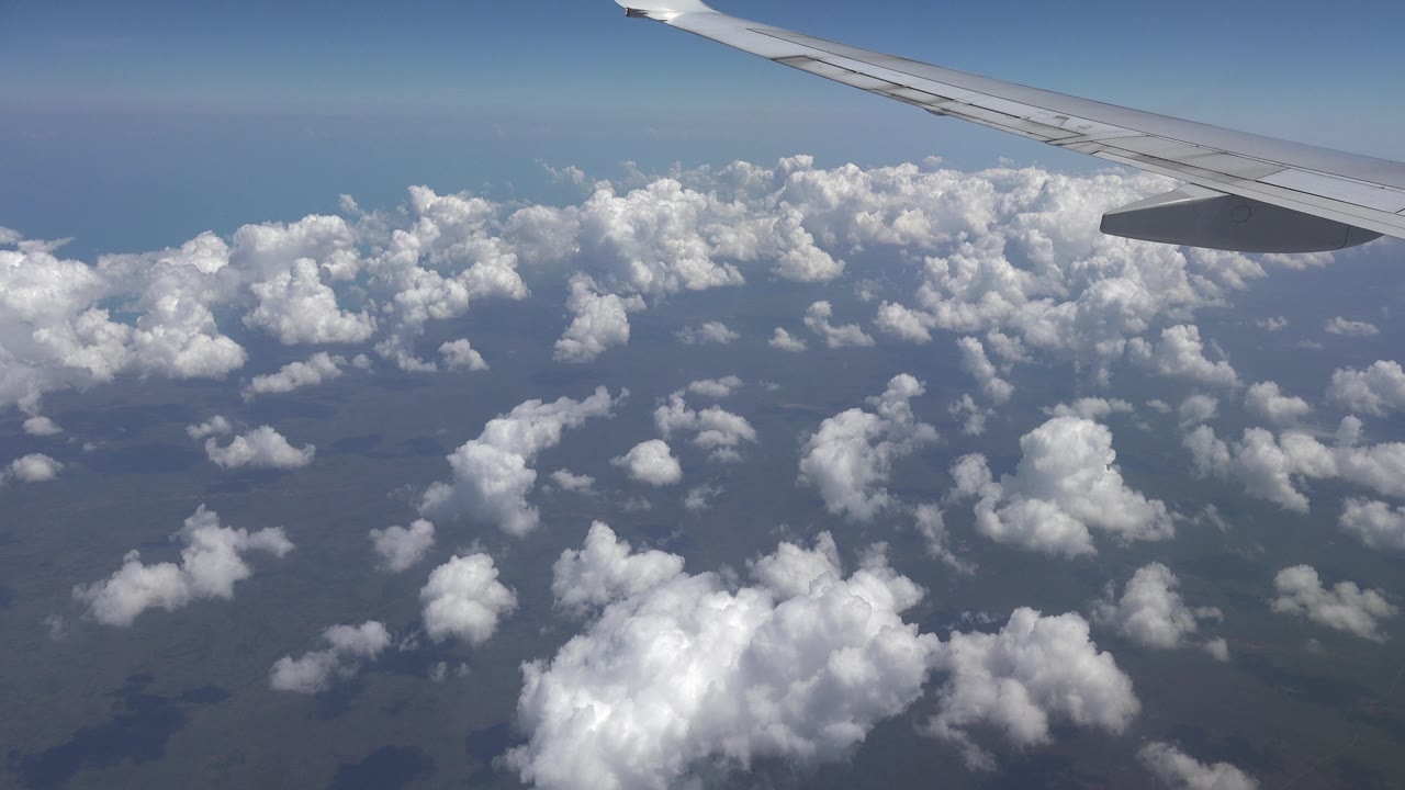 Wingtip area above layered white clouds