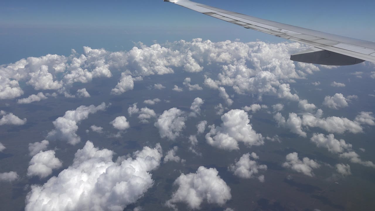 Clouds below an airplane wing in clear daylight.