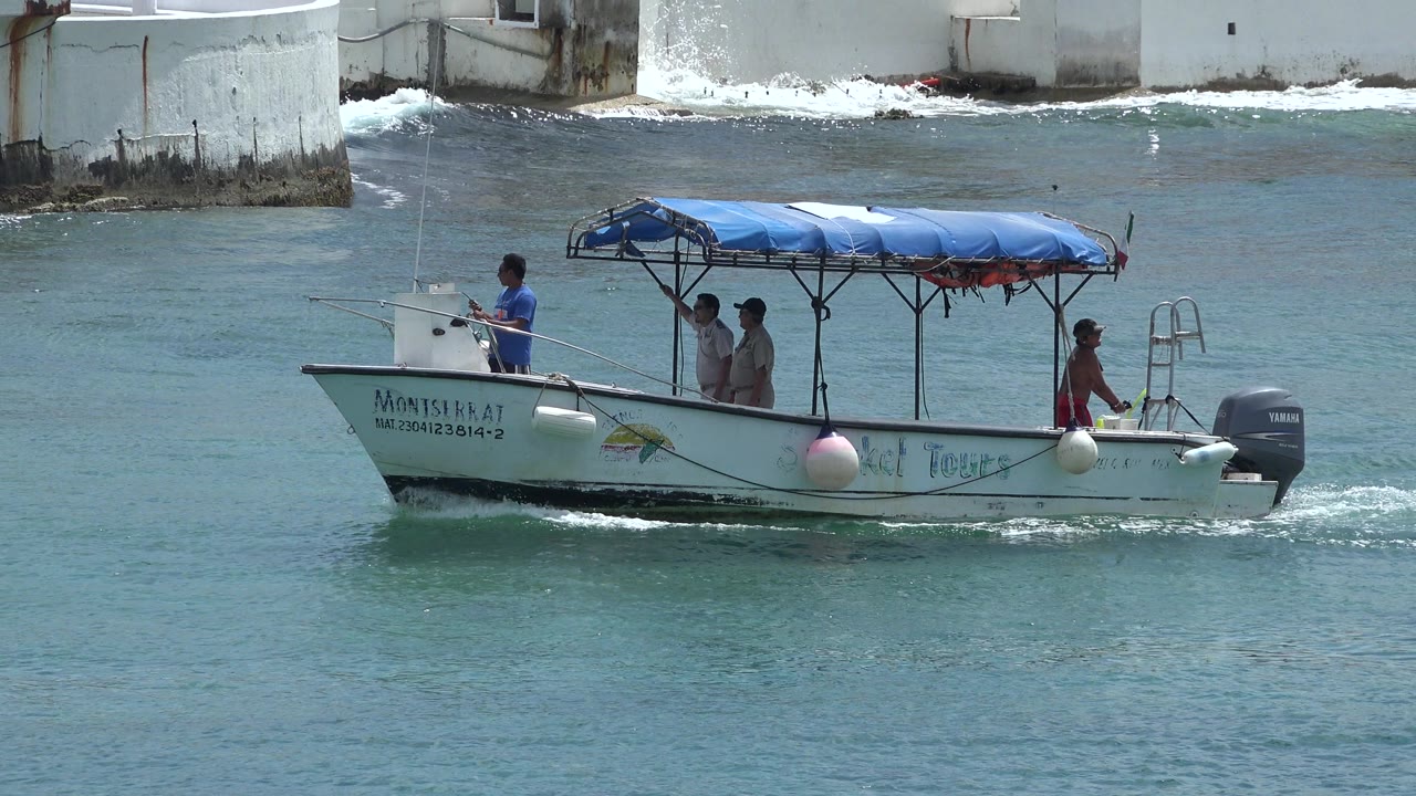 The same small passenger boat moves along the water in Playa del Carmen, Mexico, with four men aboard and wake forming behind the outboard motor.