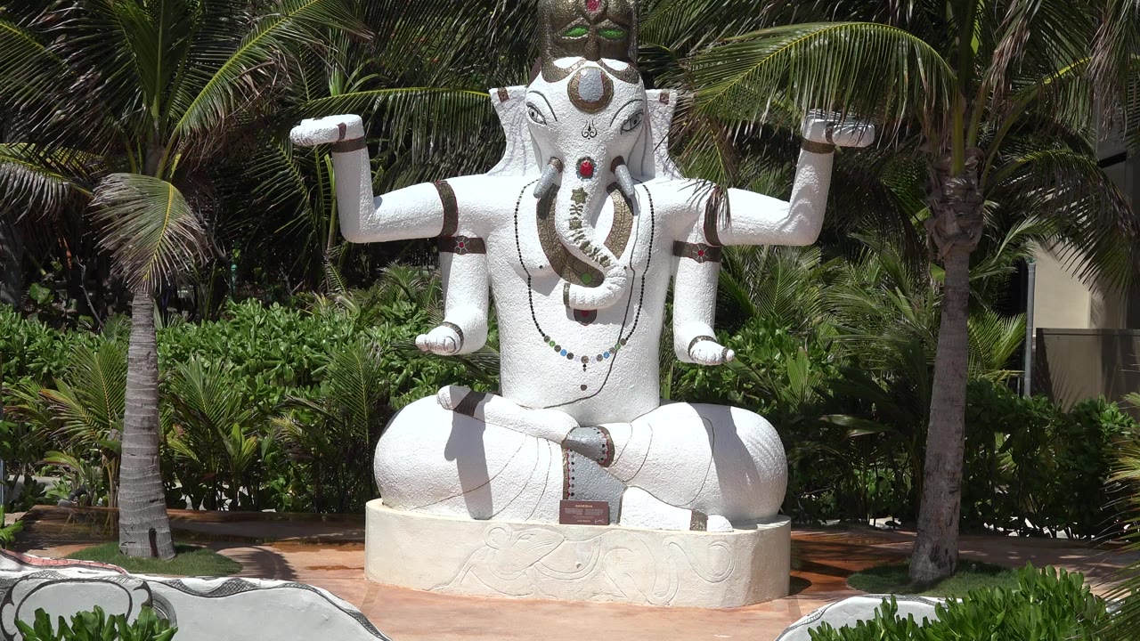 White elephant-headed statue seated in a tropical garden