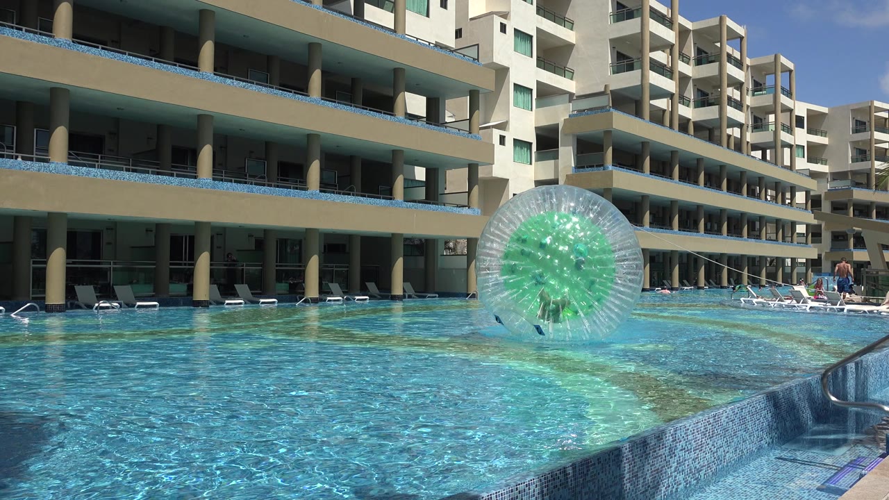 Inflatable water ball floating in a pool beside apartment buildings.