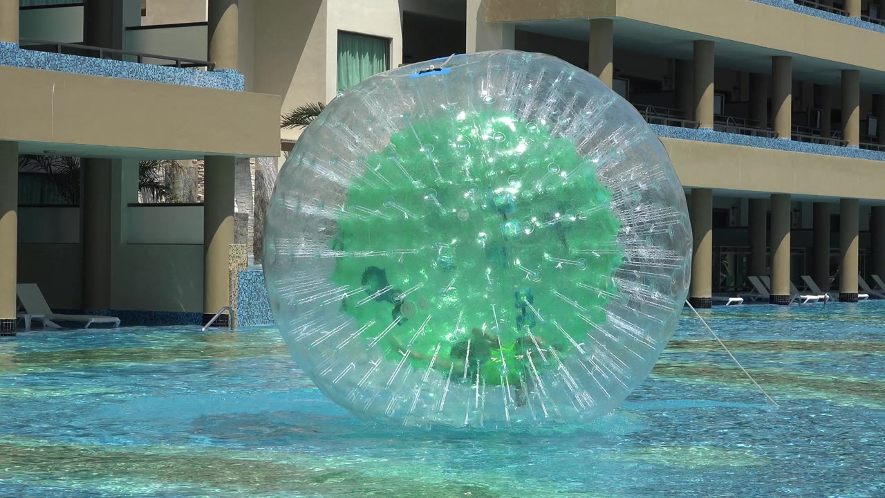 Large transparent water ball on a hotel pool with a rope or tether at the side.