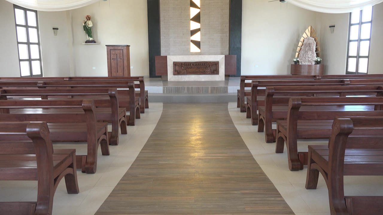Slightly later view inside the Playa Del Carmen church, showing rows of polished pews, tall side windows, the altar, and no visible people.