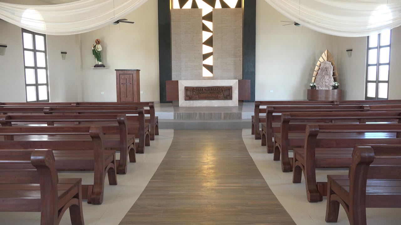 Empty church interior with wooden pews facing an altar.