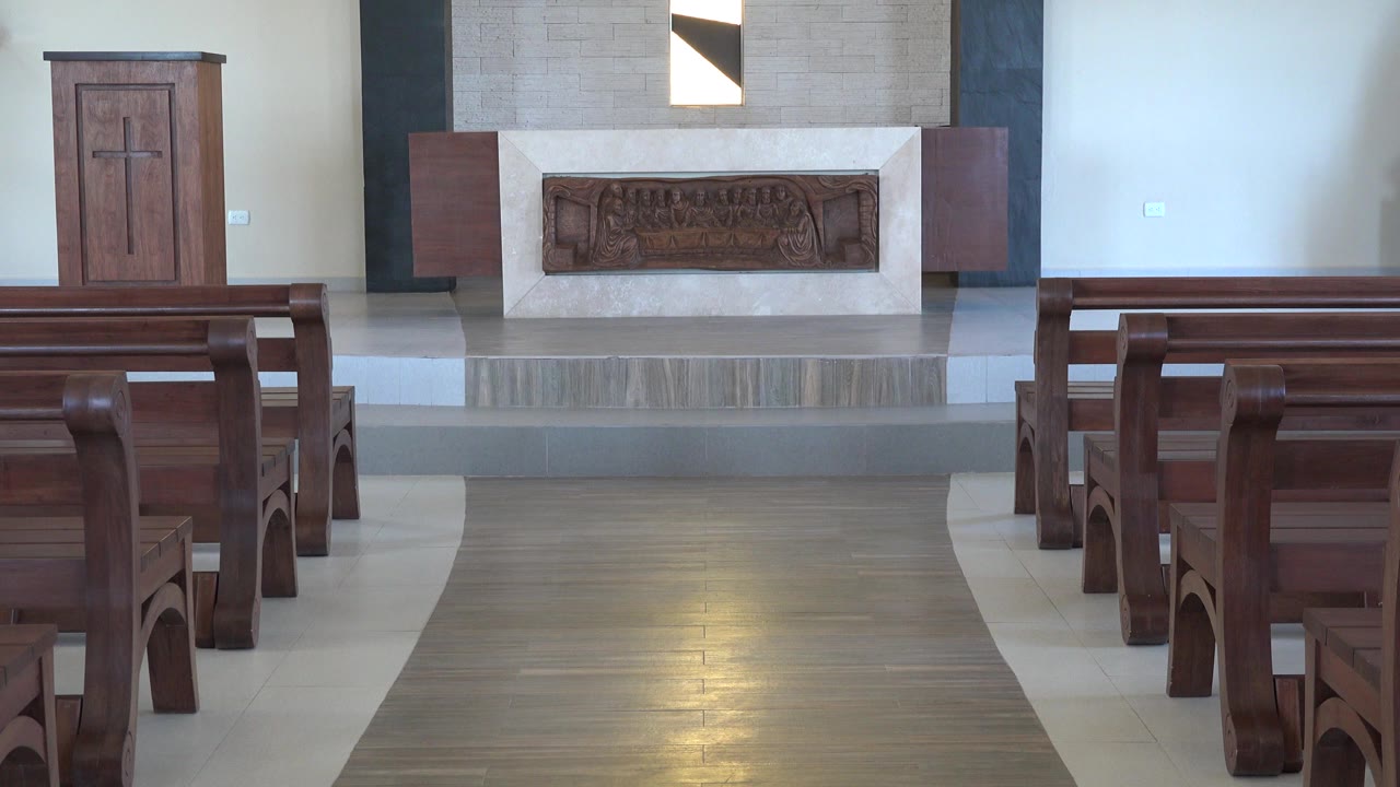 Church altar viewed over wooden pews.