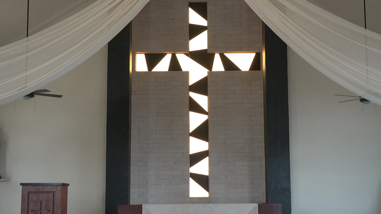Opening frame from Playa del Carmen, Mexico showing a tall brown and white geometric door or window panel beneath draped white curtains, with pale walls and no visible people.