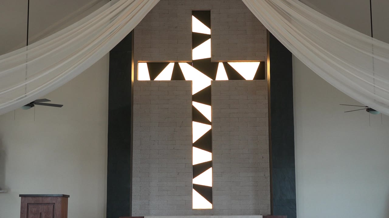 Geometric door or window panel framed by pale walls and white fabric drapes.