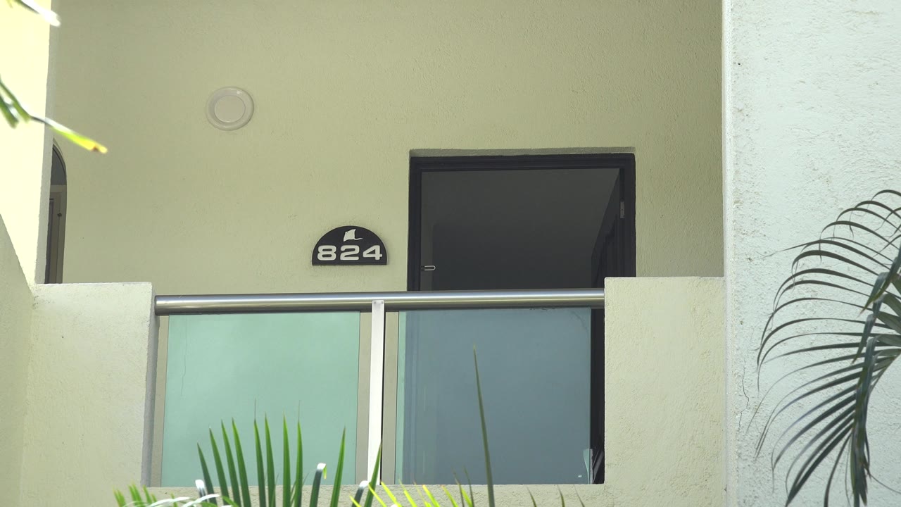 White stucco balcony with palm fronds and unit number 824.
