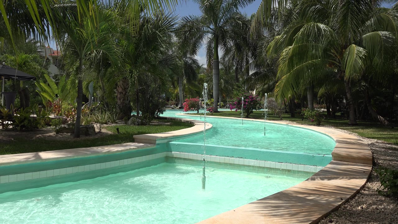 Bright pool water with palms and fountain sprays