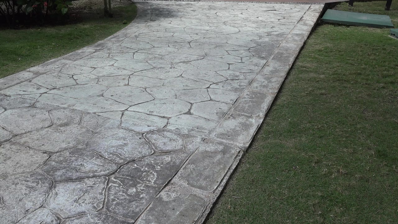 The Playa del Carmen yard view shows more of the walkway curve, a grass strip, shrubs, and a low green sign base with no visible people.