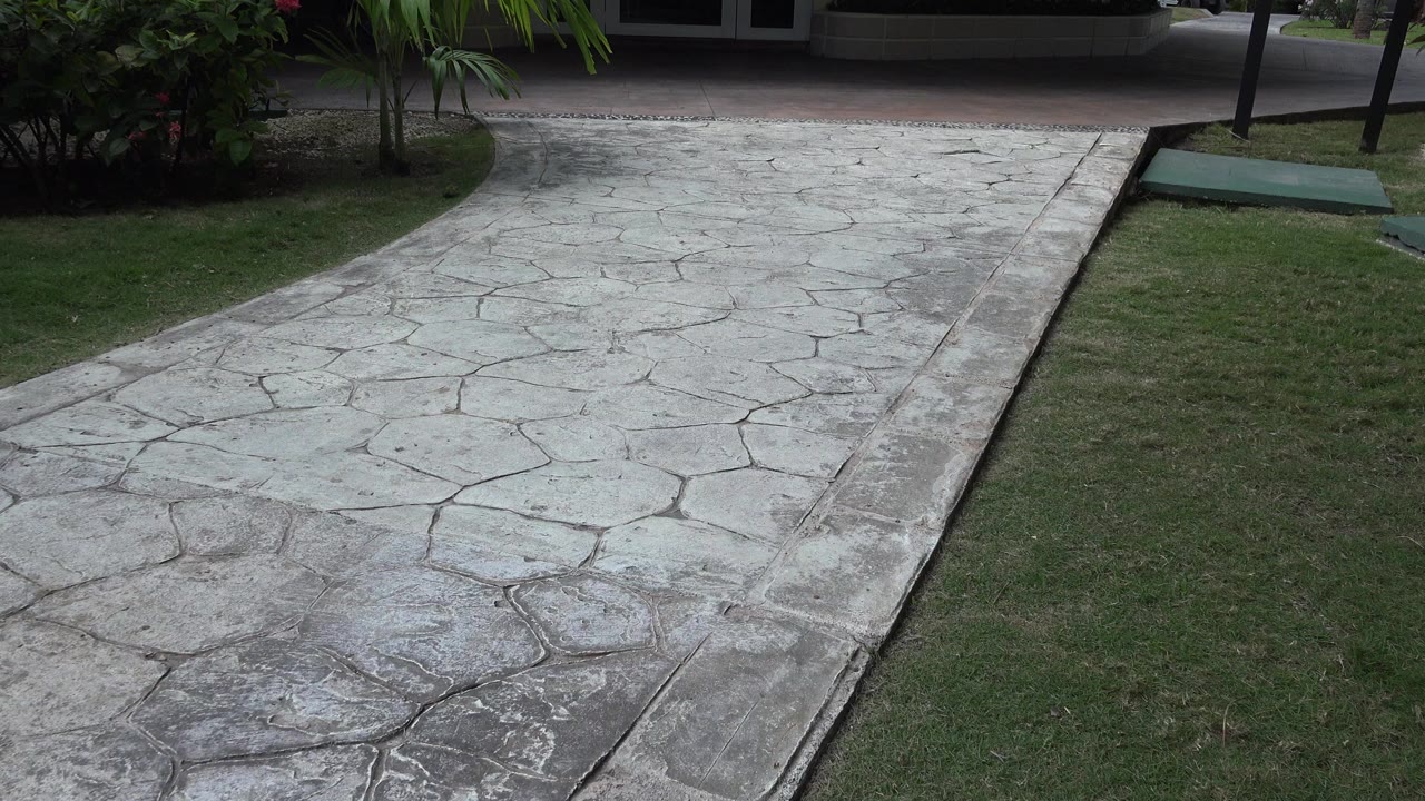 Stone-patterned walkway beside grass and shrubs