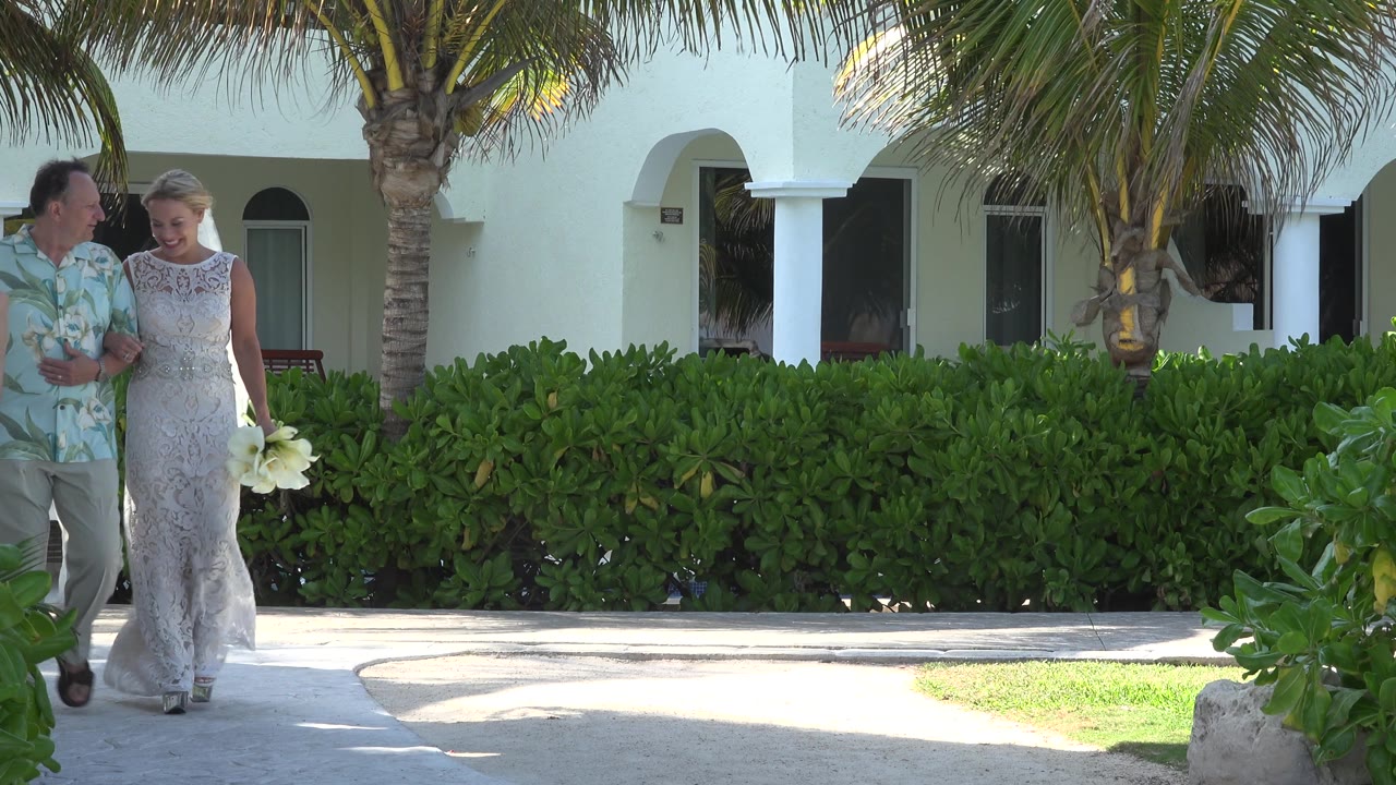 Smiling couple walking under palm fronds at a resort.