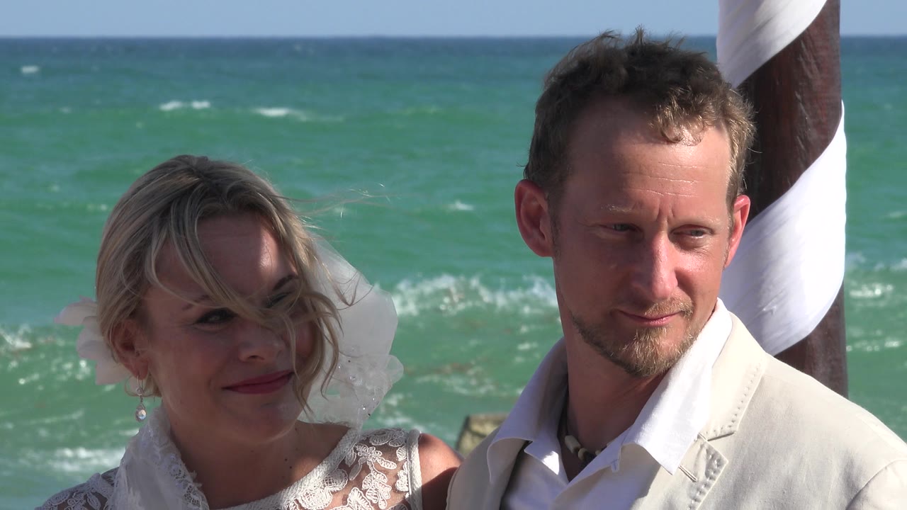Bride and groom standing by the ocean during a beach ceremony.