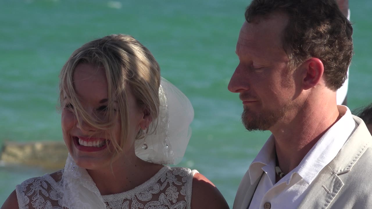 Bride laughs with hair across her face beside groom.