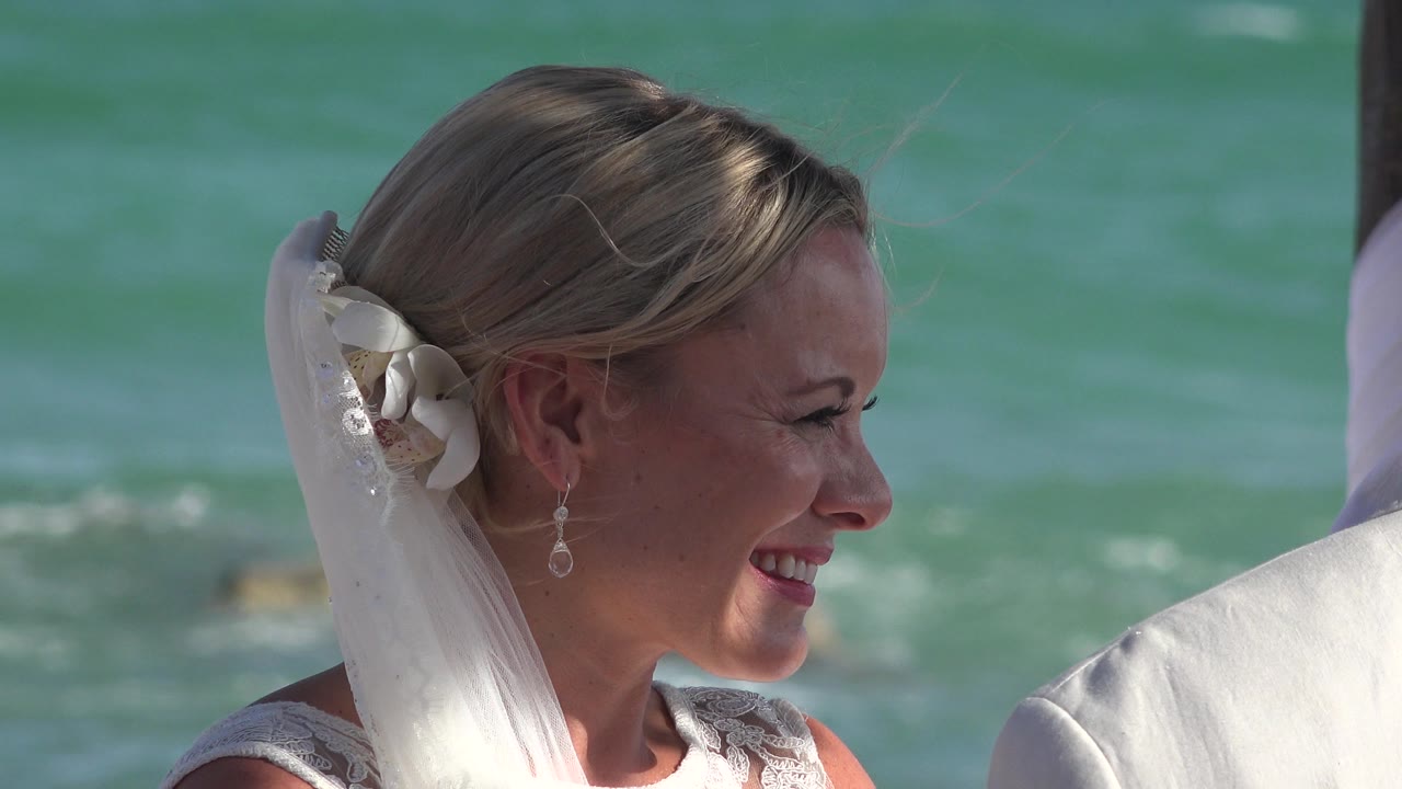 Bride smiling in profile beside ocean water